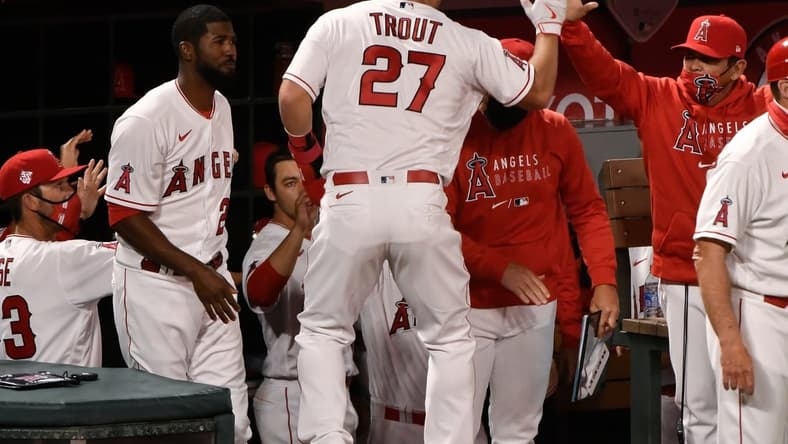 Apr 1, 2021; Anaheim, California, USA; Los Angeles Angels center fielder Mike Trout (27) is greeted at the dugout after scoring on a single by left fielder Justin Upton (not pictured) in the fourth inning against the Chicago White Sox at Angel Stadium. Mandatory Credit: Robert Hanashiro-USA TODAY Sports