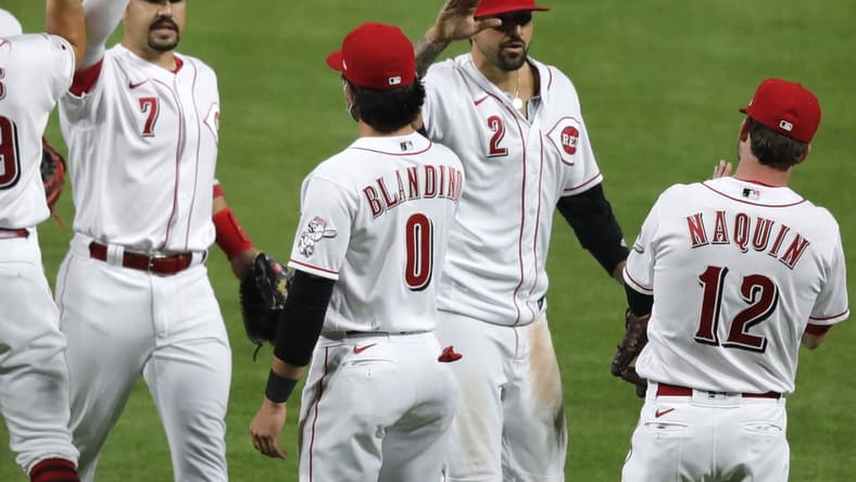 Apr 5, 2021; Cincinnati, Ohio, USA; Cincinnati Reds left fielder Nick Castellanos (2) and shortstop Eugenio Suarez (7) react with left fielder Tyler Naquin (12) and infielder Alex Blandino (0) after the Reds defeated the Pittsburgh Pirates at Great American Ball Park. Mandatory Credit: David Kohl-USA TODAY Sports