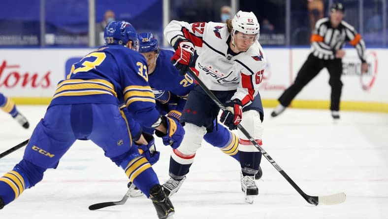 Apr 9, 2021; Buffalo, New York, USA; Buffalo Sabres defenseman Colin Miller (33) watches as Washington Capitals left wing Carl Hagelin (62) shoots the puck up ice during the first period at KeyBank Center. Mandatory Credit: Timothy T. Ludwig-USA TODAY Sports