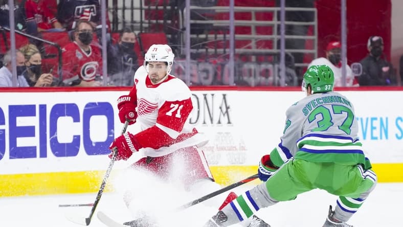 Apr 10, 2021; Raleigh, North Carolina, USA; Detroit Red Wings center Dylan Larkin (71) tries to control the puck against Carolina Hurricanes right wing Andrei Svechnikov (37) at PNC Arena. Mandatory Credit: James Guillory-USA TODAY Sports