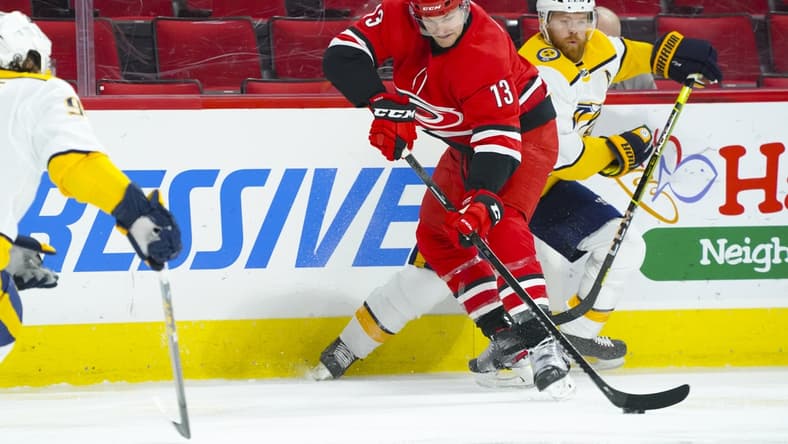 Apr 17, 2021; Raleigh, North Carolina, USA; Carolina Hurricanes left wing Warren Foegele (13) battles for the puck against Nashville Predators defenseman Ryan Ellis (4) during the first period at PNC Arena. Mandatory Credit: James Guillory-USA TODAY Sports