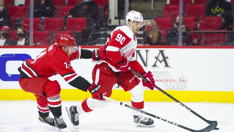 Apr 29, 2021; Raleigh, North Carolina, USA; Detroit Red Wings center Joe Veleno (90) skates with the puck past Carolina Hurricanes defenseman Brett Pesce (22) during the second period at PNC Arena. Mandatory Credit: James Guillory-USA TODAY Sports