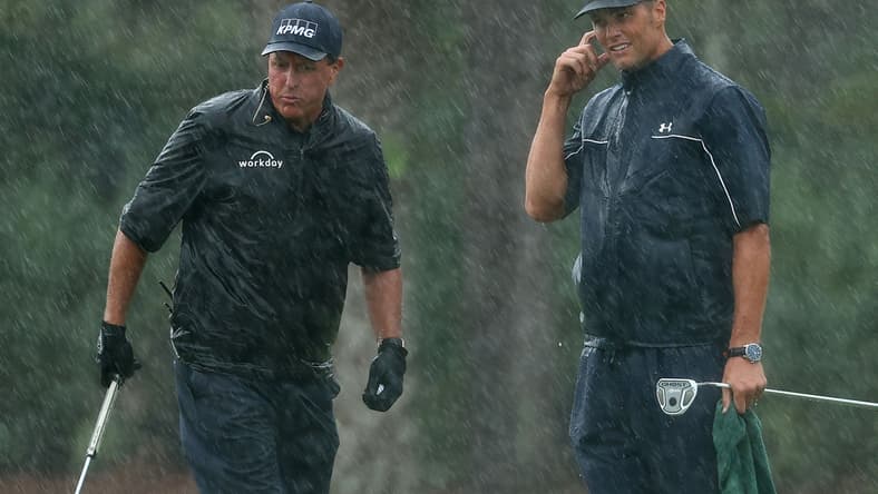 May 24, 2020; Hobe Sound, FL, USA; Phil Mickelson and NFL player Tom Brady of the Tampa Bay Buccaneers react on the 13th green in the rain during The Match: Champions for Charity golf round at the Medalist Golf Club. Mandatory Credit: Handout Photo by Getty Images for The Match via USA TODAY Sports