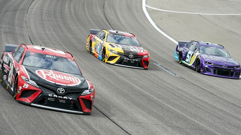 May 2, 2021; Kansas City, Kansas, USA; NASCAR Cup Series driver Kyle Busch (18) races against driver Christopher Bell (20) and driver Cody Ware (51) during the Buschy McBusch Race 400 at Kansas Speedway. Mandatory Credit: Jay Biggerstaff-USA TODAY Sports