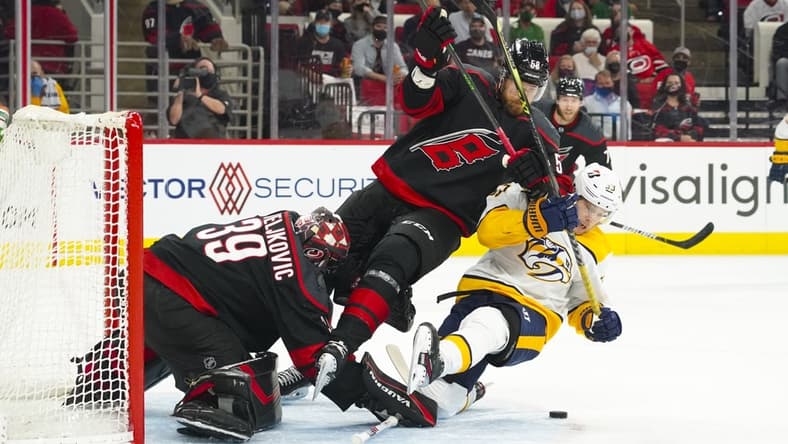 May 17, 2021; Raleigh, North Carolina, USA; Carolina Hurricanes goaltender Alex Nedeljkovic (39) and defenseman Jani Hakanpaa (58) battle Nashville Predators right wing Viktor Arvidsson (33) for the puck during the first period  in game one of the first round of the 2021 Stanley Cup Playoffs at PNC Arena. Mandatory Credit: James Guillory-USA TODAY Sports