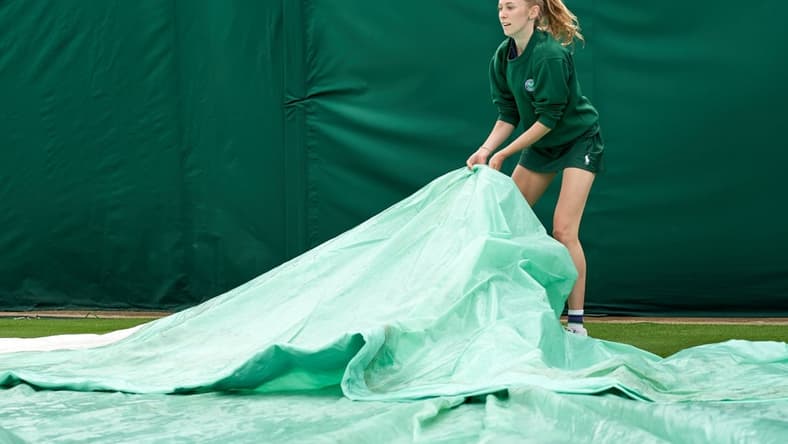 Jun 28, 2021; London, United Kingdom; A young court coverer seen at work at the rain affected start to the Championships at All England Lawn Tennis and Croquet Club. Mandatory Credit: Peter van den Berg-USA TODAY Sports
