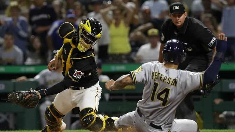 Aug 14, 2021; Pittsburgh, PA, USA; Milwaukee Brewers first baseman Jace Peterson (14) scores past Pittsburgh Pirates catcher Michael Perez (5) from second base after a throwing error by Perez on a pick-off attempt during the sixth inning at PNC Park. Mandatory Credit: Charles LeClaire-USA TODAY Sports
