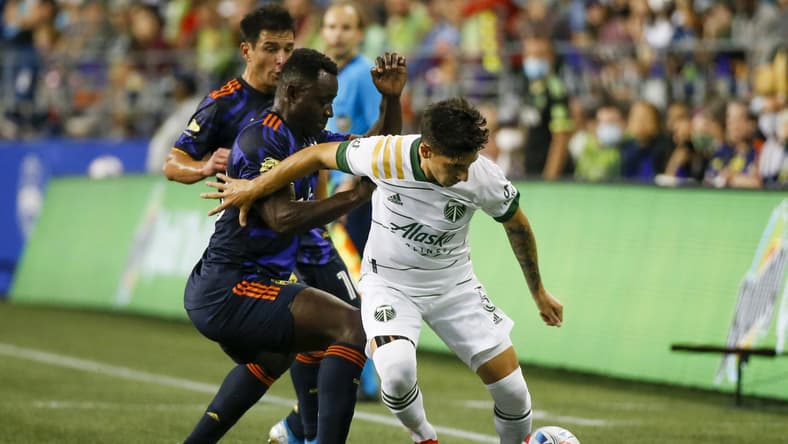 Aug 29, 2021; Seattle, Washington, USA; Portland Timbers defender Claudio Bravo (5) dribbles against Seattle Sounders FC defender Yeimar Gomez (28) during the first half at Lumen Field. Mandatory Credit: Joe Nicholson-USA TODAY Sports