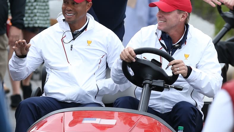 Sep 30, 2017; Jersey City, NJ, USA; (From left) Assistant captains to the U.S. team Tiger Woods and Fred Couples and Captain of the U.S. team Steve Stricker greet fans while riding in a cart during the third round foursomes matches of The President's Cup golf tournament at Liberty National Golf Course. Mandatory Credit: Bill Streicher-USA TODAY Sports