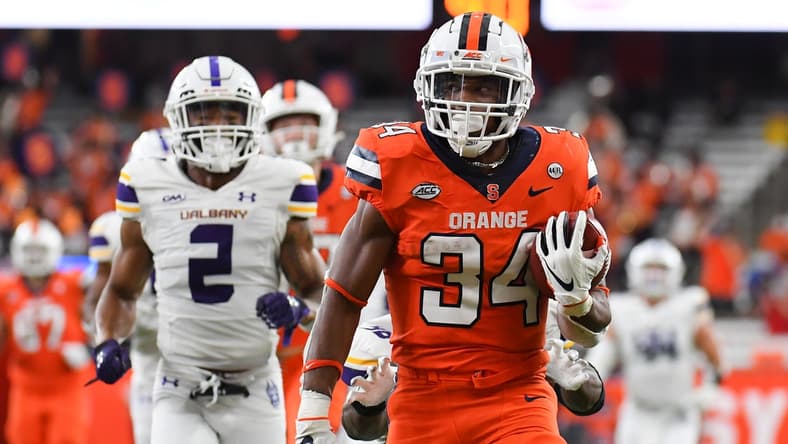 Sep 18, 2021; Syracuse, New York, USA; Syracuse Orange running back Sean Tucker (34) runs with the ball in front of Albany Great Danes defensive back Tyler Carswell (2) on his way to the end zone for a touchdown during the first half at the Carrier Dome. Mandatory Credit: Rich Barnes-USA TODAY Sports