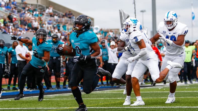 Sep 18, 2021; Buffalo, New York, USA; Coastal Carolina Chanticleers wide receiver Aaron Bedgood (3) turns the ball up field and out runs Buffalo Bulls defensive end Taylor Riggins (49) and cornerback Aapri Washington (3) to score a touchdown giving the Chanticleers an early 7-0 lead during the first quarter of play at UB Stadium. Mandatory Credit: Nicholas LoVerde-USA TODAY Sports