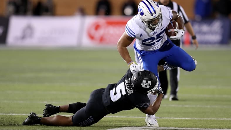 Oct 1, 2021; Logan, Utah, USA; Utah State Aggies linebacker Cash Gilliam (5) tackles Brigham Young Cougars running back Tyler Allgeier (25) during the third quarter at Merlin Olsen Field at Maverik Stadium. Mandatory Credit: Rob Gray-USA TODAY Sports