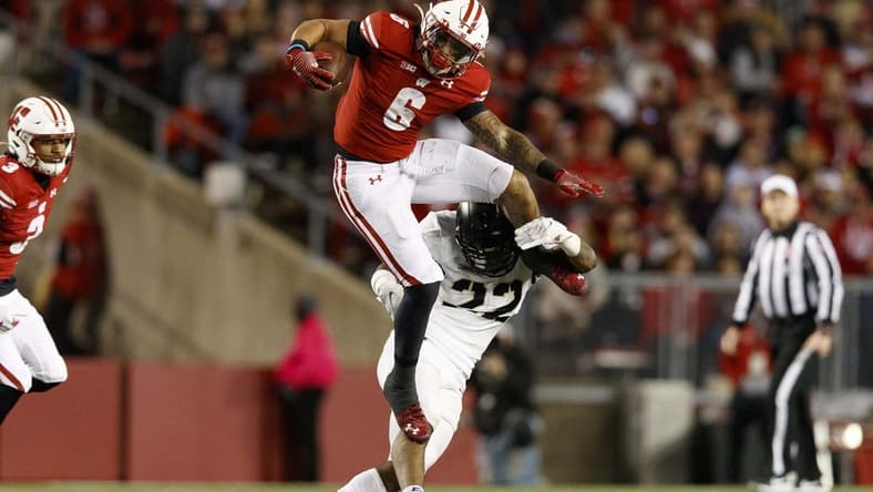 Oct 16, 2021; Madison, Wisconsin, USA;  Wisconsin Badgers running back Chez Mellusi (6) leaps over Army Black Knights defensive back Cedrick Cunningham Jr. (22) during the third quarter at Camp Randall Stadium. Mandatory Credit: Jeff Hanisch-USA TODAY Sports