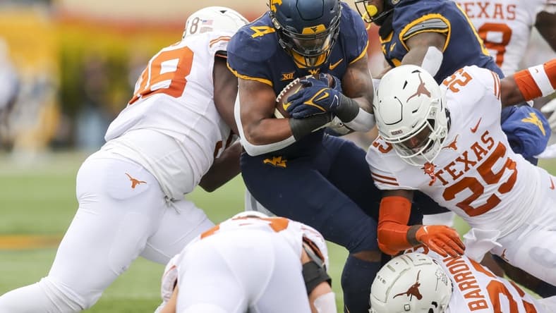 Nov 20, 2021; Morgantown, West Virginia, USA; West Virginia Mountaineers running back Leddie Brown (4) runs the ball and is tackled by many Texas Longhorns defenders during the first quarter at Mountaineer Field at Milan Puskar Stadium. Mandatory Credit: Ben Queen-USA TODAY Sports