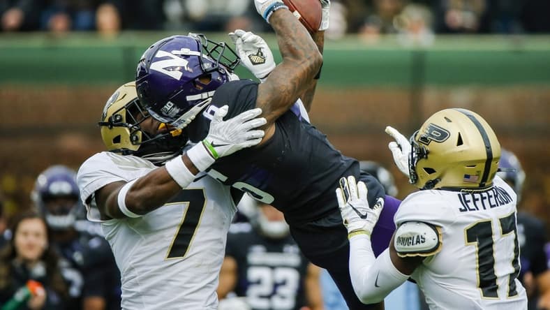 Nov 20, 2021; Chicago, Illinois, USA; Northwestern Wildcats wide receiver Malik Washington (6) catches the ball while defended by Purdue Boilermakers cornerback Jamari Brown (7) and safety Chris Jefferson (17) during the second quarter at Wrigley Field. Mandatory Credit: Jon Durr-USA TODAY Sports
