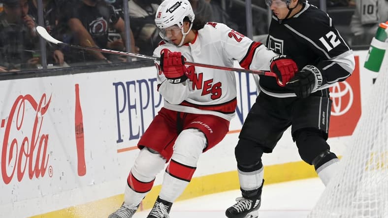 Nov 20, 2021; Los Angeles, California, USA; Carolina Hurricanes defenseman Ethan Bear (25) and Los Angeles Kings center Trevor Moore (12) battle for the puck in the second period at Staples Center. Mandatory Credit: Jayne Kamin-Oncea-USA TODAY Sports