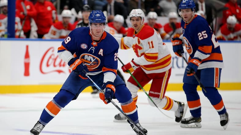 Nov 20, 2021; Elmont, New York, USA; New York Islanders center Brock Nelson (29) skates with the puck in front of Calgary Flames center Mikael Backlund (11) and Islanders defenseman Sebastian Aho (25) during the second period at UBS Arena. Mandatory Credit: Brad Penner-USA TODAY Sports