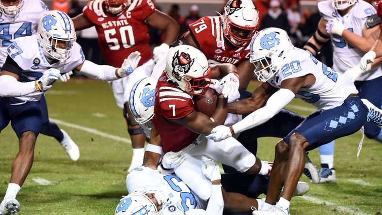 Nov 26, 2021; Raleigh, North Carolina, USA;  North Carolina State Wolfpack running back Zonovan Knight (7) is tackled after a run by North Carolina Tar Heels linebacker Cedric Gray (33) during the first half at Carter-Finley Stadium. Mandatory Credit: Rob Kinnan-USA TODAY Sports