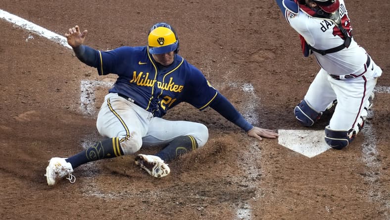 Oct 12, 2021; Cumberland, Georgia, USA; Milwaukee Brewers right fielder Avisail Garcia (left) scores a run ahead of the throw to Atlanta Braves catcher Travis d'Arnaud (16) on a single hit by catcher Omar Narvaez (not pictured) during the fourth inning during game four of the 2021 ALDS at Truist Park. Mandatory Credit: Dale Zanine-USA TODAY Sports