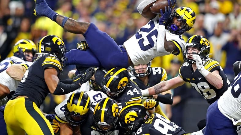 Dec 4, 2021; Indianapolis, IN, USA; Michigan Wolverines running back Hassan Haskins (25) leaps for a touchdown during the fourth quarter against the Iowa Hawkeyes in the Big Ten Conference championship game at Lucas Oil Stadium. Mandatory Credit: Mark J. Rebilas-USA TODAY Sports