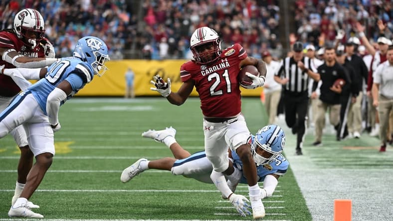 Dec 30, 2021; Charlotte, NC, USA; South Carolina Gamecocks running back Juju McDowell (21) runs for a touchdown as North Carolina Tar Heels linebacker Cedric Gray (33) defensive back Tony Grimes (20) defend in the second quarter during the 2021 Duke's Mayo Bowl at Bank of America Stadium. Mandatory Credit: Bob Donnan-USA TODAY Sports