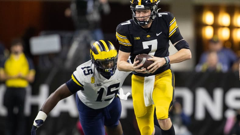 Dec 4, 2021; Indianapolis, IN, USA; Iowa Hawkeyes quarterback Spencer Petras (7) runs the ball while *Michigan Wolverines defensive lineman Christopher Hinton (15) defends in the second quarter at Lucas Oil Stadium. Mandatory Credit: Trevor Ruszkowski-USA TODAY Sports