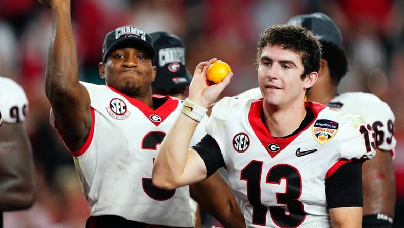 Dec 31, 2021; Miami Gardens, FL, USA; Georgia Bulldogs quarterback Stetson Bennett (13) and running back Zamir White (3) throw oranges after defeating the Michigan Wolverines in the Orange Bowl college football CFP national semifinal game at Hard Rock Stadium. Mandatory Credit: John David Mercer-USA TODAY Sports