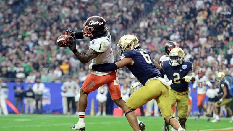 Jan 1, 2022; Glendale, Arizona, USA; Oklahoma State Cowboys wide receiver Tay Martin (1) catches a touchdown pass against Notre Dame Fighting Irish cornerback Clarence Lewis (6) during the second half of the 2022 Fiesta Bowl at State Farm Stadium. Mandatory Credit: Joe Camporeale-USA TODAY Sports