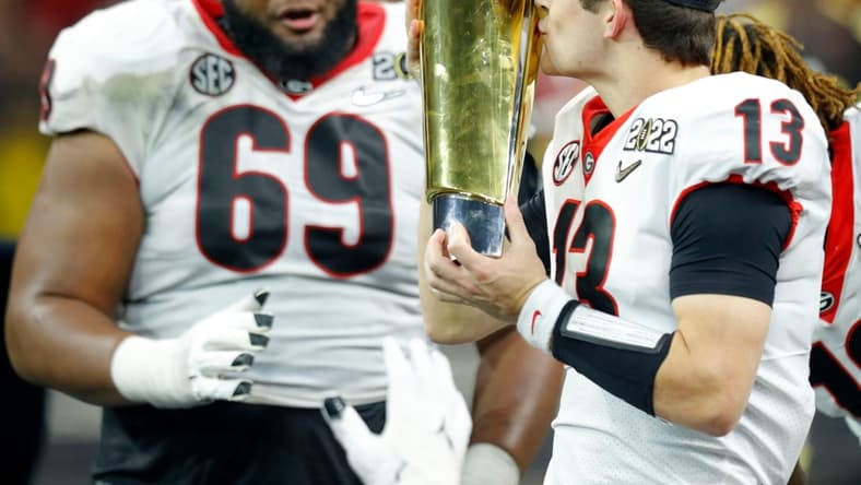 Georgia Bulldogs quarterback Stetson Bennett (13) kisses the trophy Tuesday, Jan. 11, 2022, after defeating Alabama in the College Football Playoff National Championship at Lucas Oil Stadium in Indianapolis.