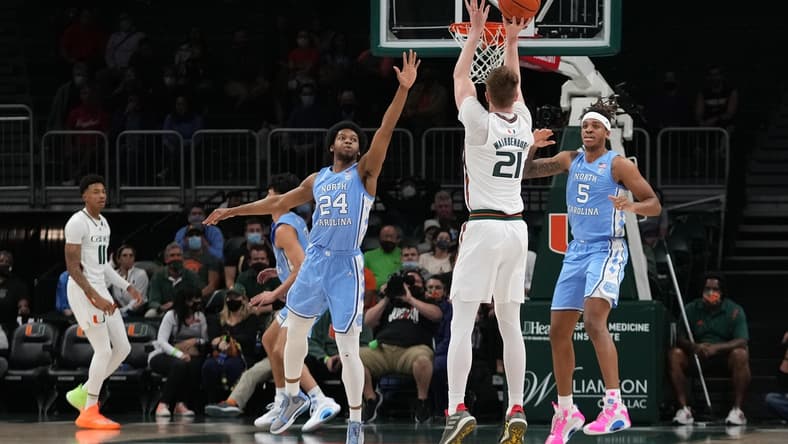 Jan 18, 2022; Coral Gables, Florida, USA; Miami Hurricanes forward Sam Waardenburg (21) attempts a three point shot over North Carolina Tar Heels guard Kerwin Walton (24) during the first half at Watsco Center. Mandatory Credit: Jasen Vinlove-USA TODAY Sports