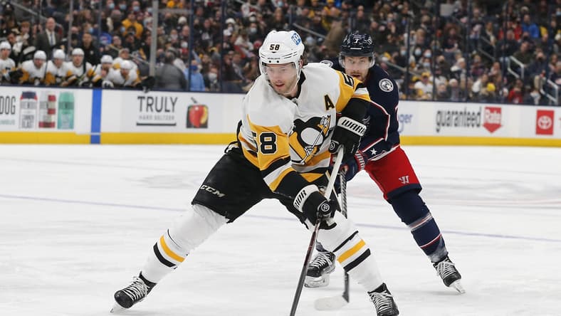 Jan 21, 2022; Columbus, Ohio, USA; Pittsburgh Penguins defenseman Kris Letang (58) passes the puck as Columbus Blue Jackets center Sean Kuraly (7) trails the play during the first period at Nationwide Arena. Mandatory Credit: Russell LaBounty-USA TODAY Sports
