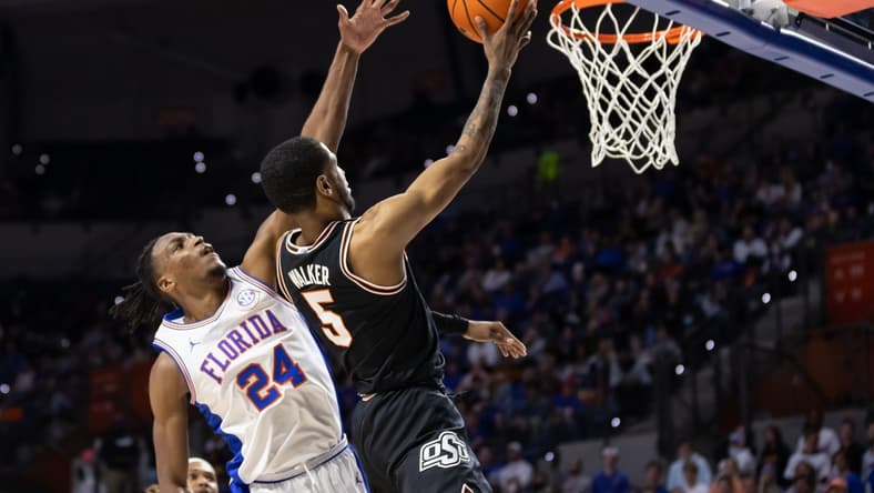 Jan 29, 2022; Gainesville, Florida, USA; Oklahoma State Cowboys guard Rondel Walker (5) makes a layup over Florida Gators guard Phlandrous Fleming Jr. (24) during the first half at Billy Donovan Court at Exactech Arena. Mandatory Credit: Matt Pendleton-USA TODAY Sports