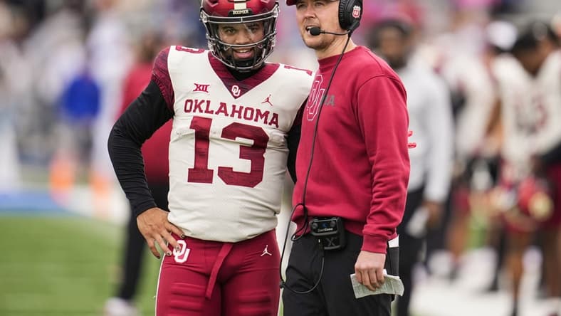 Oct 23, 2021; Lawrence, Kansas, USA; Oklahoma Sooners quarterback Caleb Williams (13) talks with head coach Lincoln Riley during the second half against the Kansas Jayhawks at David Booth Kansas Memorial Stadium. Mandatory Credit: Jay Biggerstaff-USA TODAY Sports