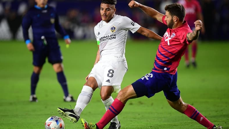 Oct 23, 2021; Carson, California, USA; Los Angeles Galaxy midfielder Jonathan dos Santos (8) moves the ball against FC Dallas midfielder Ryan Hollingshead (12) during the first half at StubHub Center. Mandatory Credit: Gary A. Vasquez-USA TODAY Sports