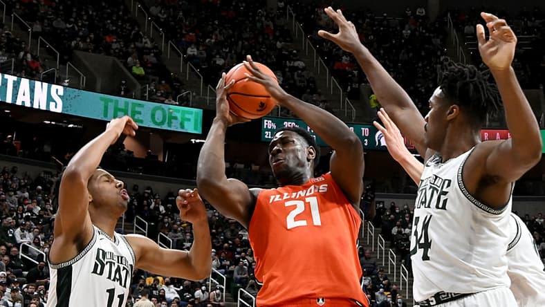 Feb 19, 2022; East Lansing, Michigan, USA; Illinois Fighting Illini center Kofi Cockburn (21) grabs a rebound in the first half against Michigan State Spartans guard A.J. Hoggard (11) and forward Julius Marble II (34) at Jack Breslin Student Events Center. Mandatory Credit: Dale Young-USA TODAY Sports
