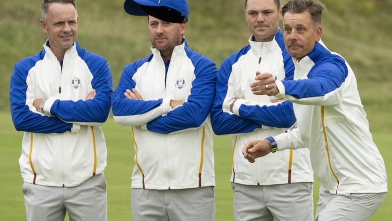 September 21, 2021; Kohler, Wisconsin, USA; Team Europe vice-captain Henrik Stenson (far right) tosses his hat as Luke Donald (far left), Graeme McDowell (second from left), and Martin Kaymer (third from left) look on while posing for a team photo during a practice round for the 43rd Ryder Cup golf competition at Whistling Straits. Mandatory Credit: Kyle Terada-USA TODAY Sports