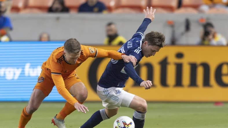 Mar 12, 2022; Houston, Texas, USA; Houston Dynamo FC defender Adam Lundkvist (3) chases Vancouver Whitecaps FC midfielder Ryan Gauld (25) in the first half at PNC Stadium. Mandatory Credit: Thomas Shea-USA TODAY Sports