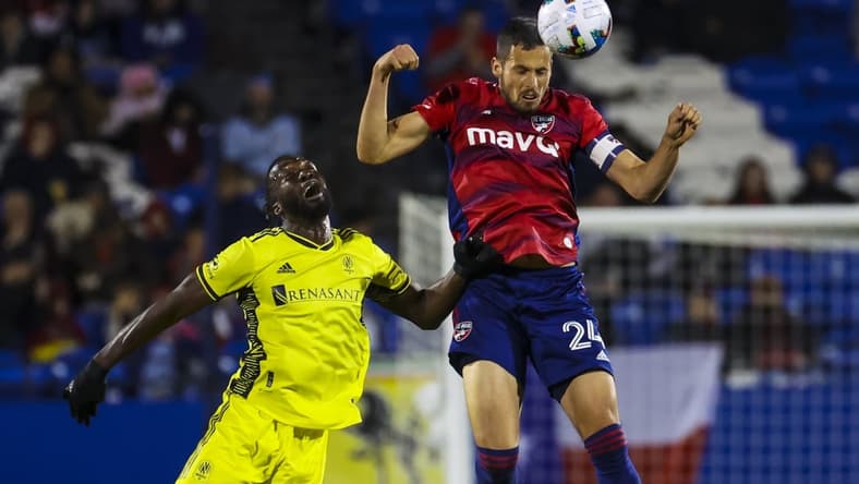 Mar 12, 2022; Frisco, Texas, USA;  FC Dallas defender Matt Hedges (24) heads the ball away from Nashville SC forward C.J. Sapong (17) during the first half at Toyota Stadium. Mandatory Credit: Kevin Jairaj-USA TODAY Sports