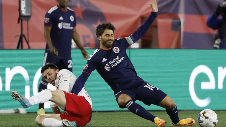 Apr 2, 2022; Foxborough, Massachusetts, USA; New England Revolution midfielder Carles Gil (10) is taken down by New York Red Bulls midfielder Lewis Morgan (10) during the first half at Gillette Stadium. Mandatory Credit: Winslow Townson-USA TODAY Sports