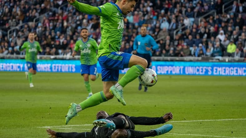 Apr 2, 2022; Saint Paul, Minnesota, USA; Seattle Sounders midfielder Alex Roldan (16) leaps over Minnesota United defender Bakaye Dibassy (12) in the first half at Allianz Field. Mandatory Credit: Matt Blewett-USA TODAY Sports