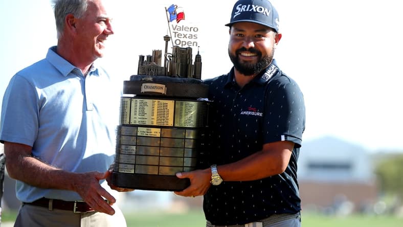 Apr 3, 2022; San Antonio, Texas, USA; J.J. Spaun (right) poses with a tournament official while holding the champion's trophy after winning Valero Texas Open golf tournament. Mandatory Credit: Erik Williams-USA TODAY Sports