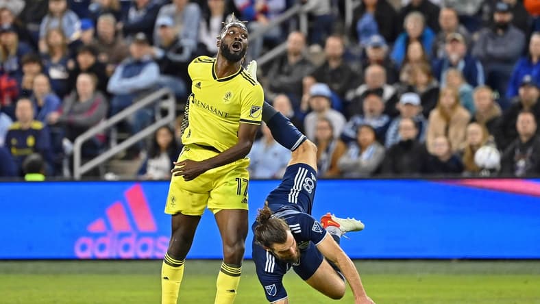 Apr 9, 2022; Kansas City, Kansas, USA; Sporting Kansas City defender Graham Zusi (8) is upended after making a play for the ball against Nashville SC forward C.J. Sapong (17) during the first half at Children's Mercy Park. Mandatory Credit: Peter Aiken-USA TODAY Sports