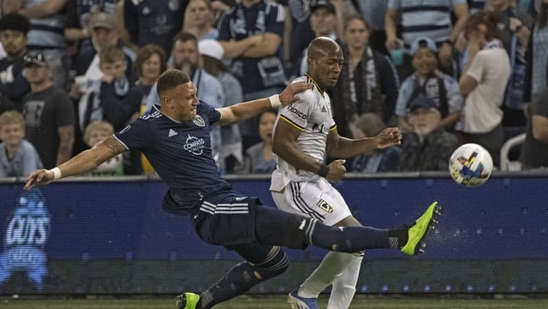 Apr 23, 2022; Kansas City, Kansas, USA; Sporting Kansas City defender Kortne Ford (12) clears the ball away from Columbus Crew midfielder Darlington Nagbe (6) during the first half at Children's Mercy Park. Mandatory Credit: Peter Aiken-USA TODAY Sports