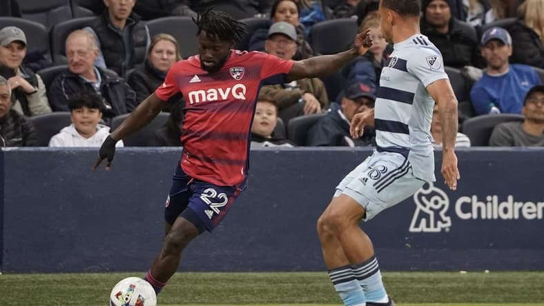 Apr 30, 2022; Kansas City, Kansas, USA; FC Dallas midfielder Ema Twumasi (22) passes the ball against Sporting Kansas City defender Logan Ndenbe (18) during the first half at Children's Mercy Park. Mandatory Credit: Denny Medley-USA TODAY Sports