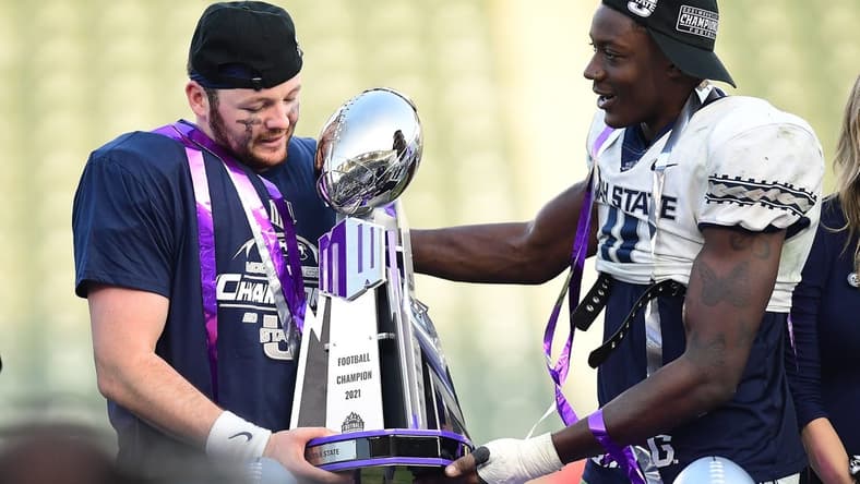 Dec 4, 2021; Carson, CA, USA; Utah State Aggies quarterback Logan Bonner (1) and defensive end Byron Vaughns (11) hold the champions trophy following the victory against the San Diego State Aztecs in the Mountain West Conference championship game at Dignity Health Sports Park. Mandatory Credit: Gary A. Vasquez-USA TODAY Sports