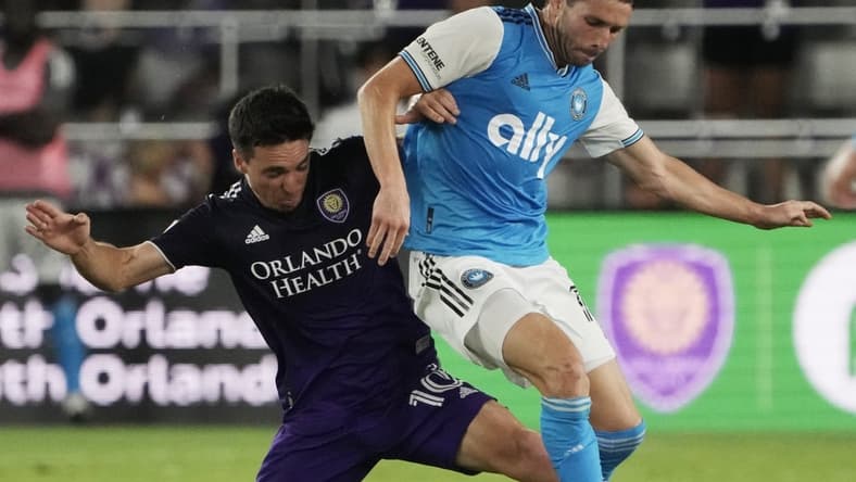Apr 30, 2022; Orlando, Florida, USA; Orlando City midfielder Mauricio Pereyra (10) tackles Charlotte FC midfielder Brandt Bronico (13) during the second half at Exploria Stadium. Mandatory Credit: Kirby Lee-USA TODAY Sports
