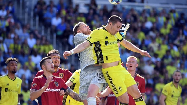 May 8, 2022; Nashville, Tennessee, USA; Nashville SC midfielder Alex Muyl (19) collides with Real Salt Lake goalkeeper Zac MacMath (18) on a corner kick during the first half at Geodis Park. Mandatory Credit: Christopher Hanewinckel-USA TODAY Sports