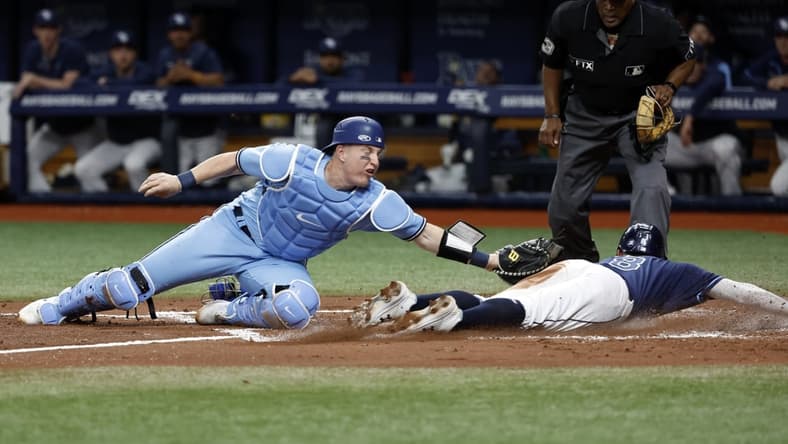 May 13, 2022; St. Petersburg, Florida, USA; Tampa Bay Rays second baseman Brandon Lowe (8) slides into home plate safe as Toronto Blue Jays catcher Tyler Heineman (22) attempted to tag him out during the second inning at Tropicana Field. Mandatory Credit: Kim Klement-USA TODAY Sports