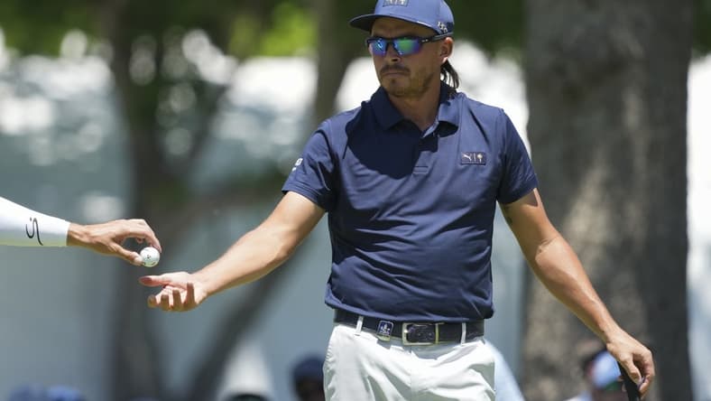 May 16, 2022; Tulsa, Oklahoma, USA; Rickie Fowler gets his ball from his caddie on the 3rd green during a practice round for the PGA Championship golf tournament at Southern Hills Country Club. Mandatory Credit: Michael Madrid-USA TODAY Sports