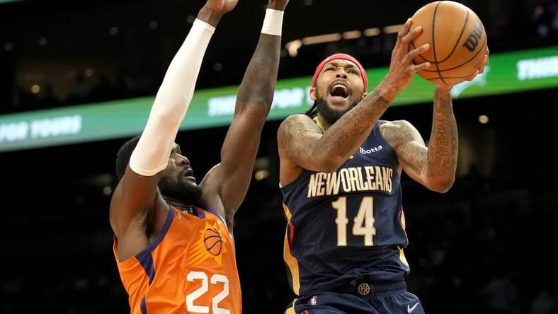 Feb 25, 2022; Phoenix, Arizona, USA; New Orleans Pelicans forward Brandon Ingram (14) drives past Phoenix Suns center Deandre Ayton (22) in the first half at Footprint Center. Mandatory Credit: Rick Scuteri-USA TODAY Sports